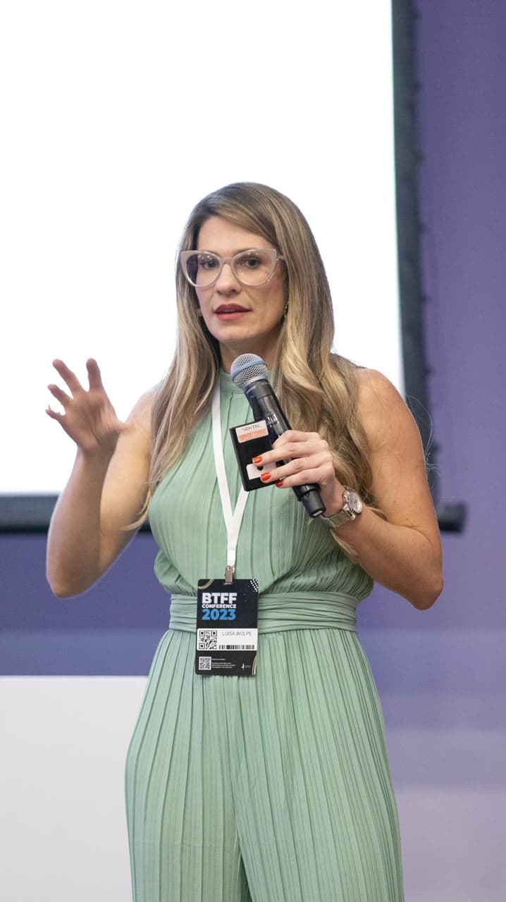 Luisa Wolpe palestrando na BTFF Conference 2023, com crachá oficial do evento